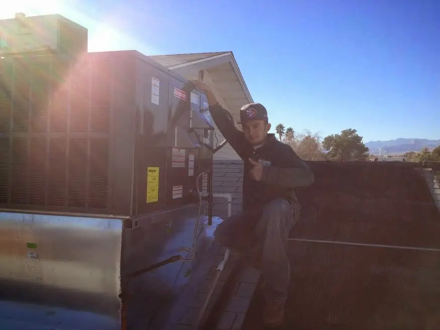 HVAC technician performing Air Duct Cleaning on a rooftop unit in Robinson
